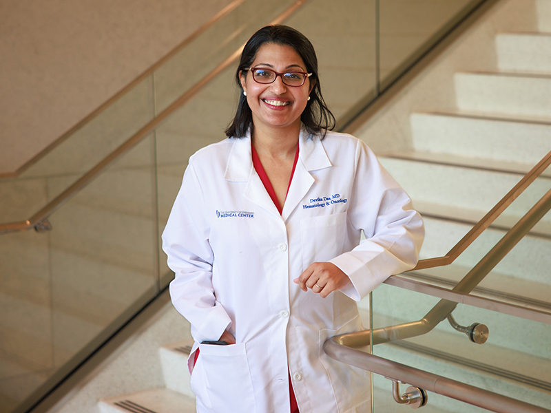 Dr. Das leaning on a stair rail in the School of Medicine.